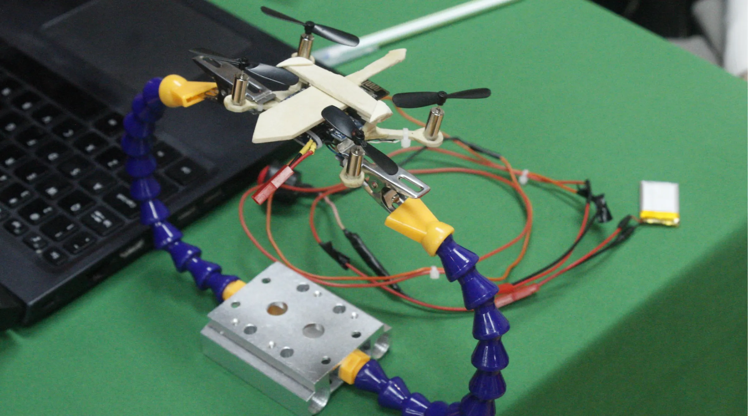 Mô hình drone siêu nhỏ được lắp ráp từ các linh kiện cơ bản, nổi bật với thiết kế khung hình thanh kiếm và hệ thống điều khiển do sinh viên tự phát triển