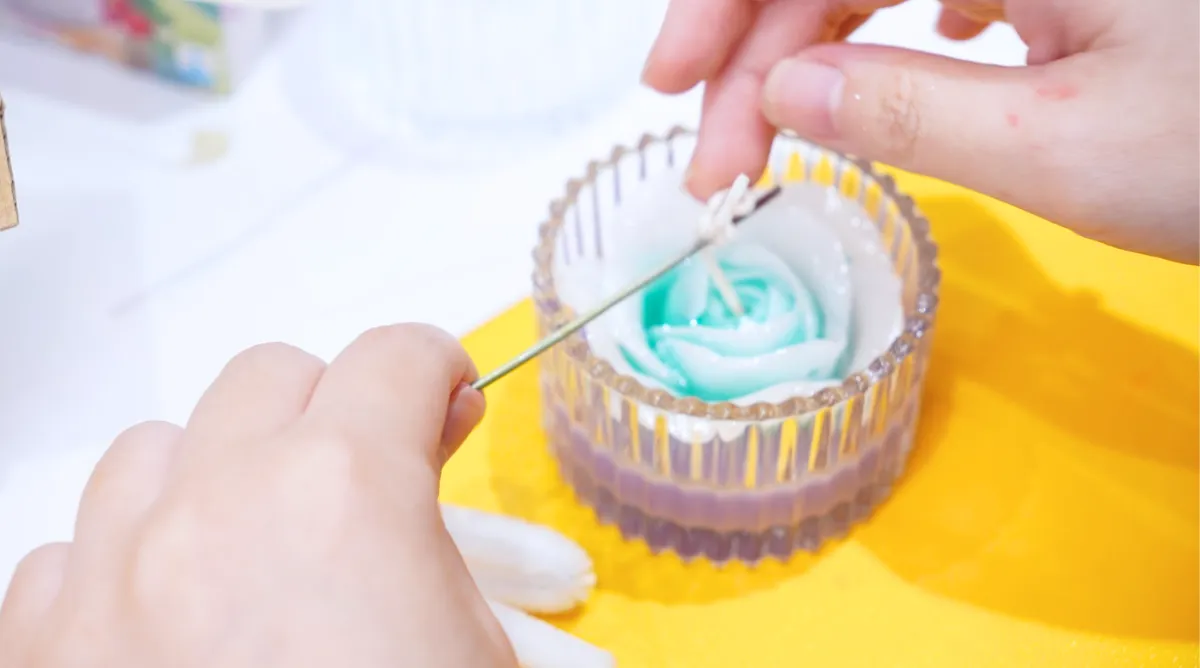Người tham gia tỉ mỉ hoàn thiện sản phẩm nến thơm tạo hình bông hoa, thể hiện sự khéo léo và sáng tạo tại "Bloom Workshop"